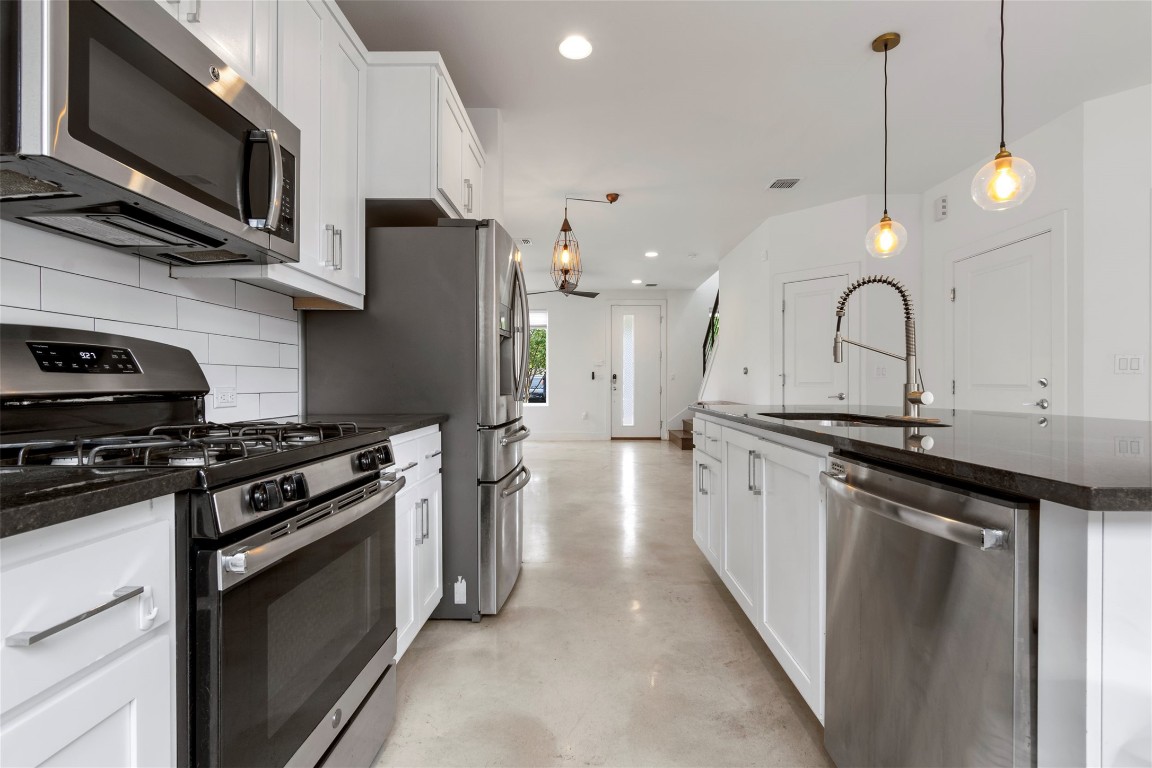 1145 Shady Lane, Unit 1A Austin, TX 78721 - Photo 18 of 25 Sleek white kitchen with large island, stainless steel appliances, and pendant lighting.