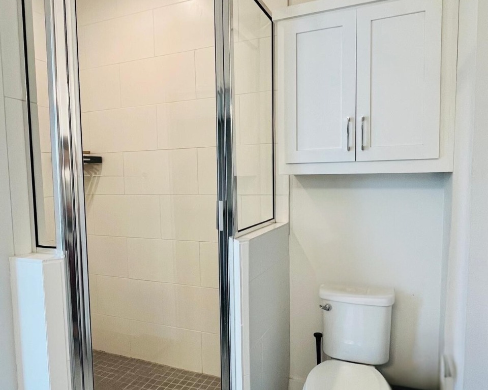 1145 Shady Lane, Unit 1A Austin, TX 78721 - Photo 6 of 25 Primary Bathroom – Modern and bright with granite counters, dual vanities, a walk-in glass shower, and ample storage—designed for both function and style.