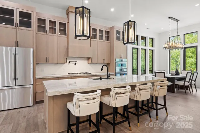 a kitchen with stainless steel appliances granite countertop a table chairs and a refrigerator