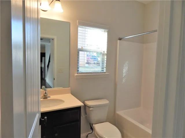 a view of an empty room with wooden floor and a ceiling fan