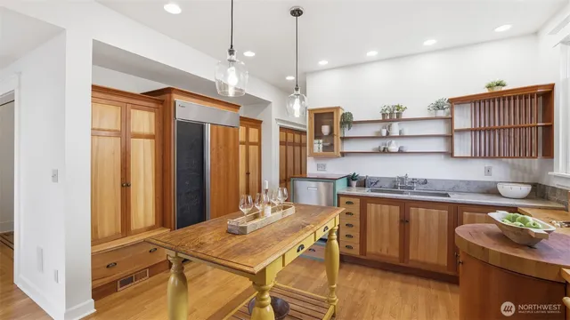 a kitchen with stainless steel appliances granite countertop a sink a stove a refrigerator and island with wooden floor