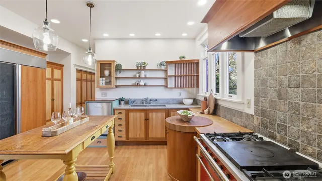 a kitchen with stainless steel appliances a stove a sink dishwasher and a dining table with wooden floor