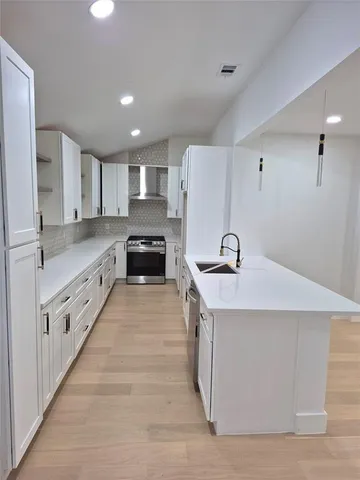 a large white kitchen with stainless steel appliances