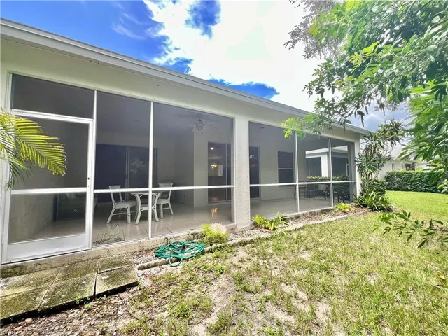a view of a house with a large window and a yard with potted plants