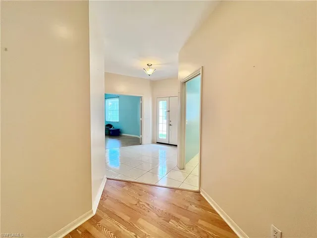 a view of a hallway with wooden floor and a bathroom