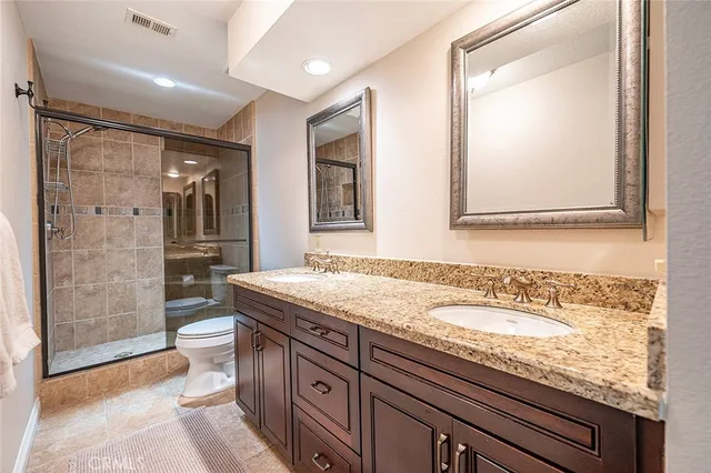 a bathroom with a granite countertop sink a toilet a mirror and shower