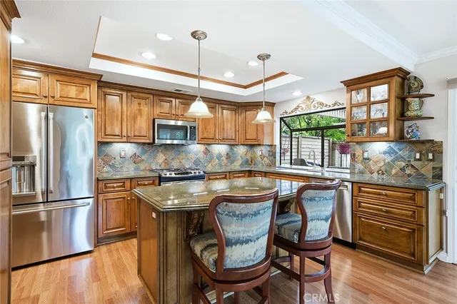 a kitchen with stainless steel appliances granite countertop a stove a refrigerator a oven a sink with island chairs and wooden cabinets