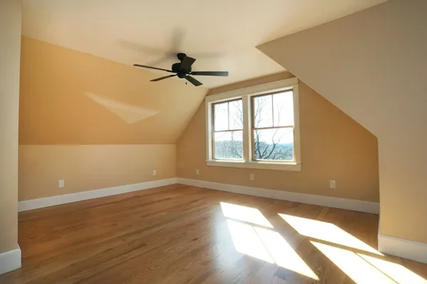 a view of empty room with wooden floor and fan