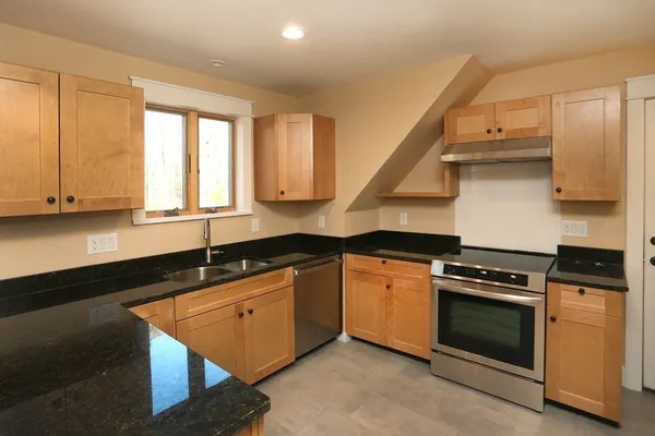 a kitchen with granite countertop a stove a sink and a cabinet