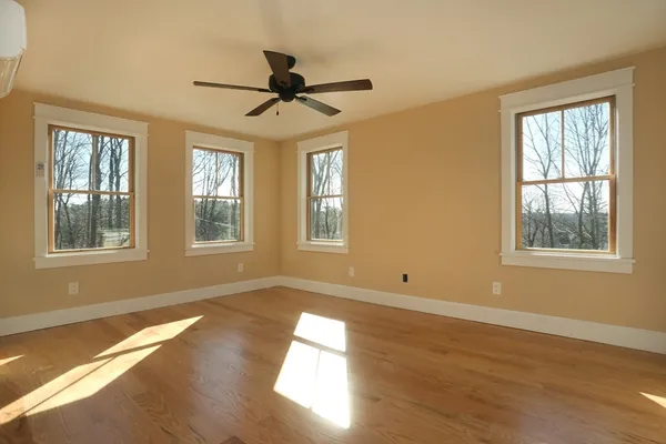 a view of empty room with wooden floor and fan