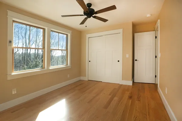 a view of an empty room with a window and wooden floor