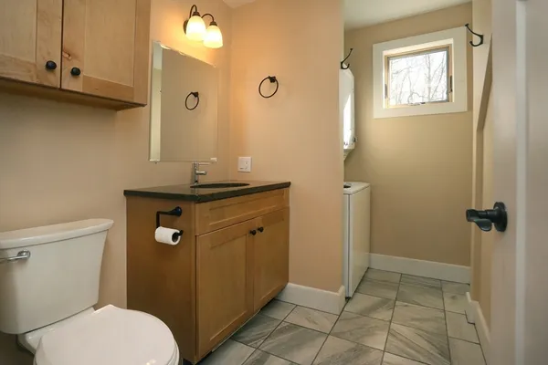 a bathroom with a granite countertop sink a toilet a mirror and shower