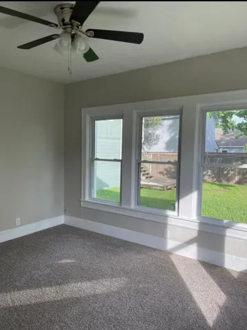 a view of an empty room with a window and a ceiling fan