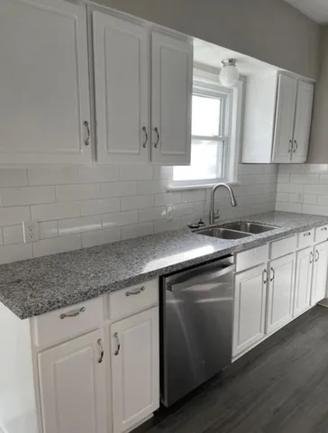 a kitchen with granite countertop white cabinets white appliances and a sink