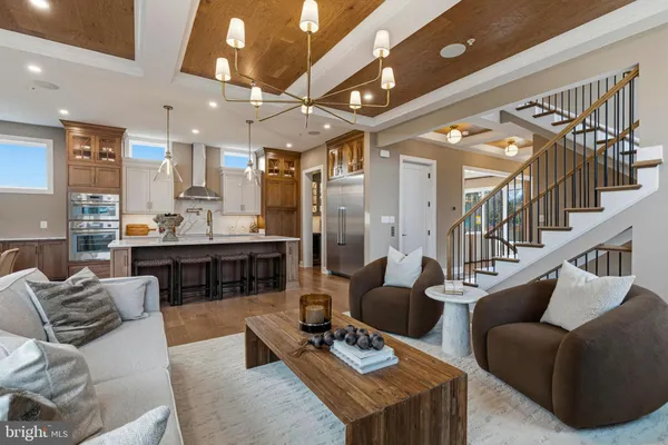 a living room with furniture kitchen view and a chandelier