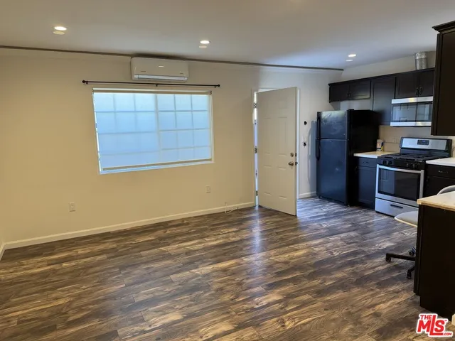 an empty room with wooden floor and stainless steel appliances