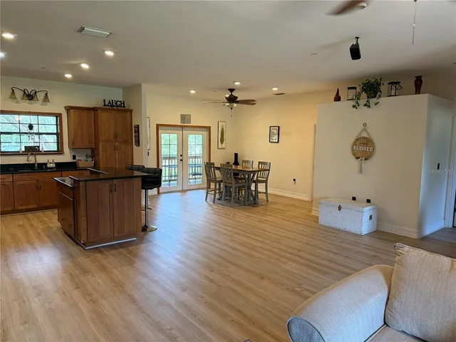 a living room with furniture kitchen view and a wooden floor