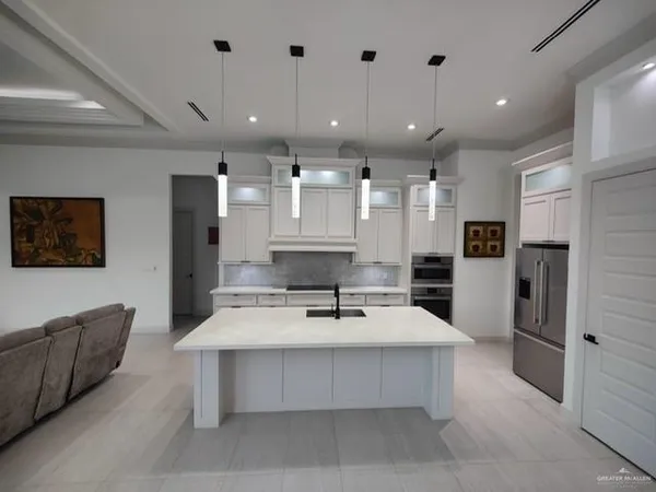 a dining hall with stainless steel appliances kitchen island granite countertop a couch and cabinets