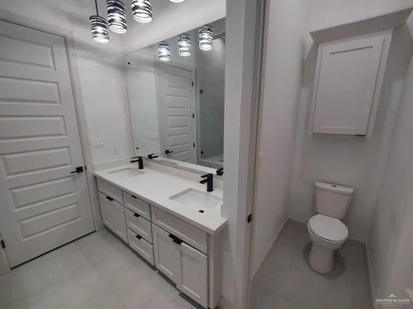 a spacious bathroom with a double vanity sink a toilet and a mirror