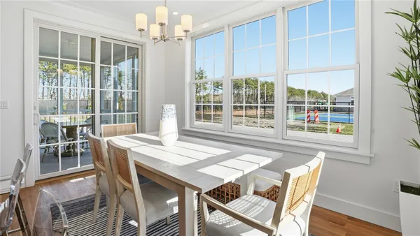 a dining room with wooden floor a chandelier a wooden table and chairs