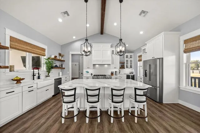 a kitchen with stainless steel appliances kitchen island granite countertop a stove top oven a refrigerator cabinets and dining table view