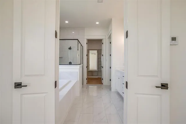 a view of a hallway with white walls and wooden floors
