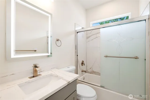 a bathroom with a granite countertop sink mirror vanity and toilet