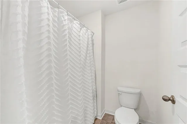 a bathroom with a toilet and a shower curtain