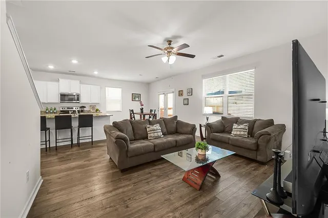 a living room with furniture kitchen view and a wooden floor
