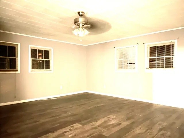 a view of an empty room with wooden floor and chandelier