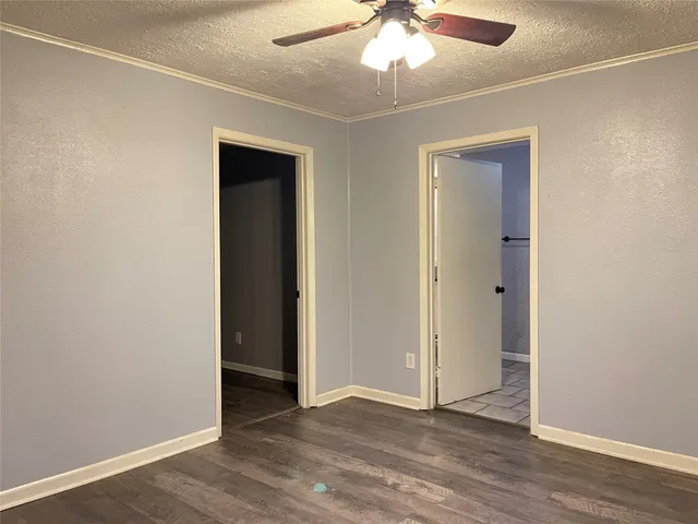 an empty room with wooden floor chandelier fan and closet area