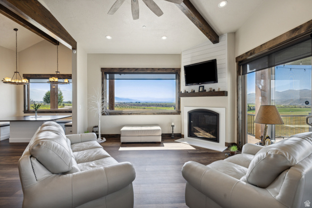 6117 North Rocky Ridge Road Peoa, UT 84061 - Photo 37 of 82 Living area featuring expansive windows, wood-finish flooring, a corner fireplace with shiplap accent wall, and a ceiling fan