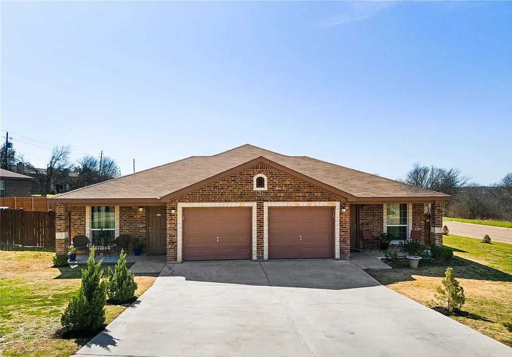 a front view of a house with a yard and potted plants