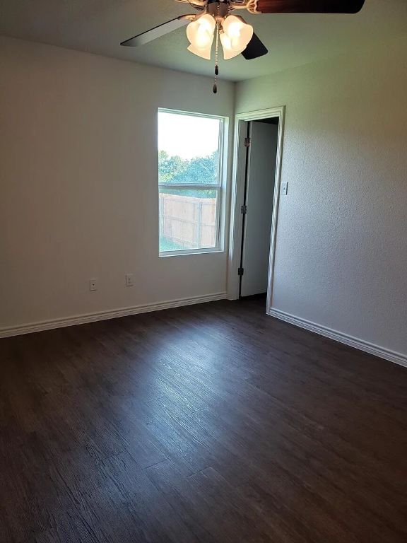 895 Twin Oaks Drive, Unit B Temple, TX 76504 - Photo 8 of 11 an empty room with wooden floor chandelier fan and windows