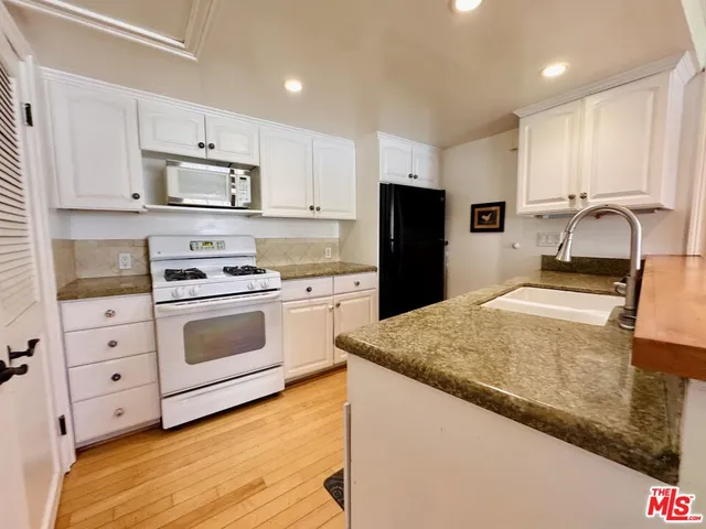a kitchen with granite countertop a sink stove and refrigerator