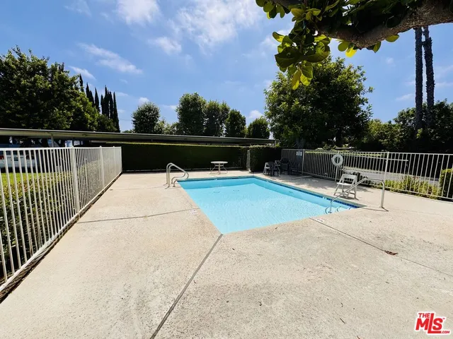 a view of a swimming pool with a bench and trees