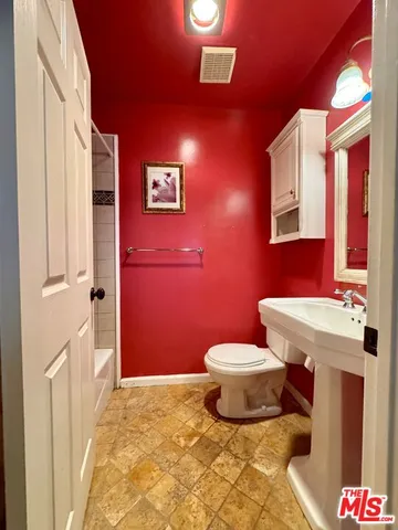 a bathroom with a granite countertop toilet sink and mirror