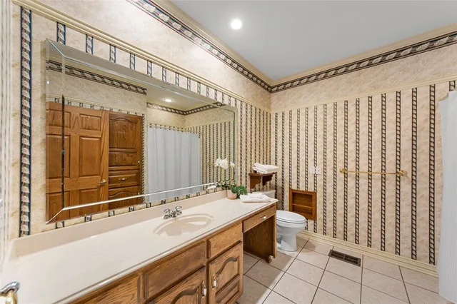 an empty room with chandelier fan and kitchen view