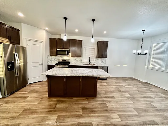 a kitchen with kitchen island a sink stainless steel appliances and a counter top space