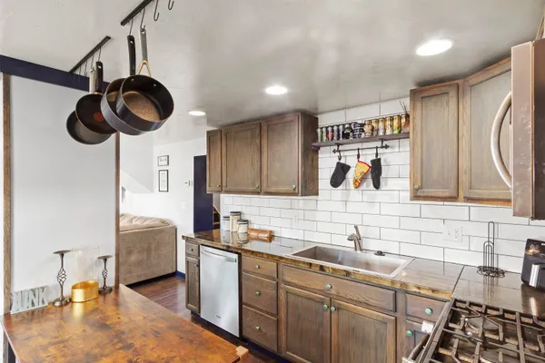 a kitchen with stainless steel appliances granite countertop a sink a stove and a wooden floors