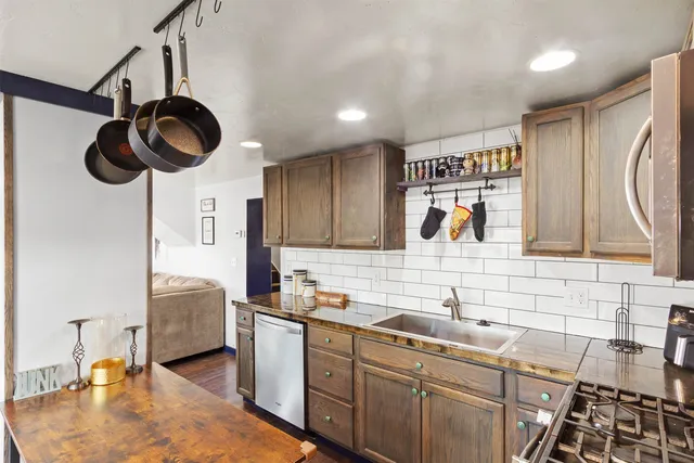 a kitchen with stainless steel appliances granite countertop a sink a stove and a wooden floors