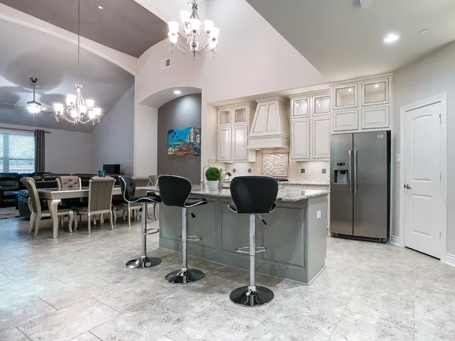 a kitchen with stainless steel appliances kitchen island granite countertop furniture a refrigerator a stove a dining table and chairs