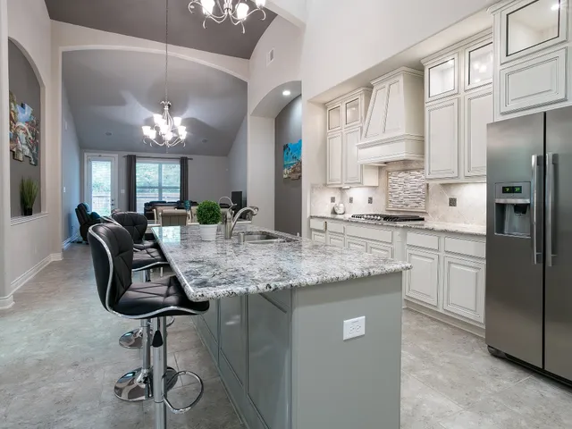 a kitchen with stainless steel appliances granite countertop a sink a stove a refrigerator cabinets and chairs