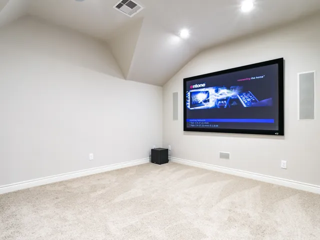 a bedroom with a bed and a flat tv screen on dresser