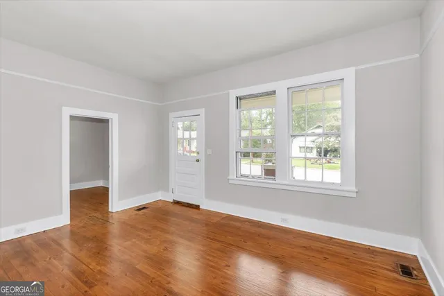 an empty room with wooden floor and windows