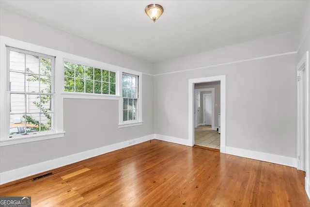 a view of an empty room with wooden floor and a window
