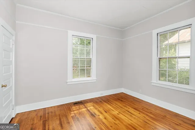 an empty room with wooden floor and windows
