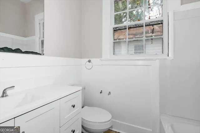 a bathroom with a toilet a sink a vanity and mirror