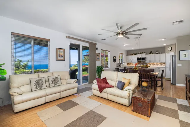 a living room with furniture kitchen view and a chandelier