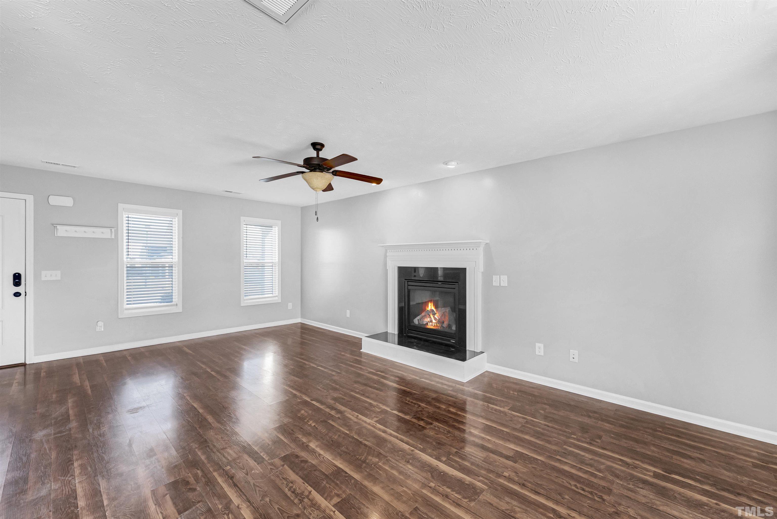 707 Botanical Court Bunnlevel, NC 28323 - Photo 6 of 31 a view of an empty room with wooden floor fireplace and a window